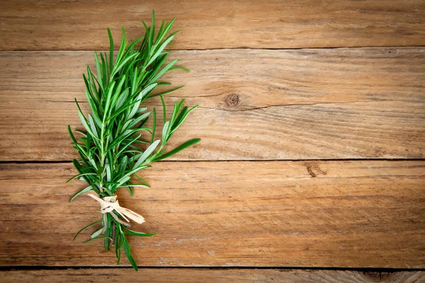 Rosemary bir ahşap arka plan üzerinde bağlı. — Stok fotoğraf