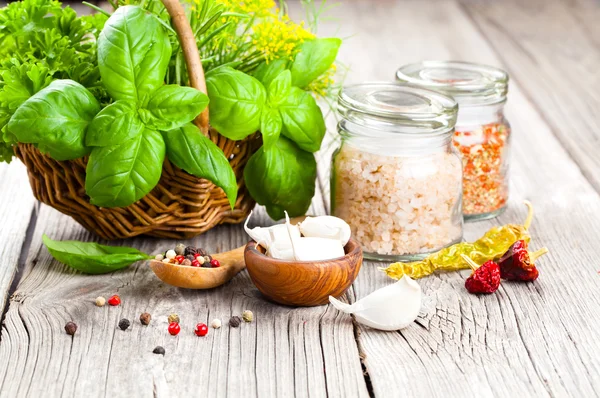 Especias: ajo, sal, pimienta y albahaca sobre un fondo de madera — Foto de Stock