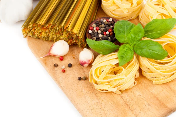 Ninho de macarrão italiano fettuccine com folhas de manjericão fresco, em branco — Fotografia de Stock