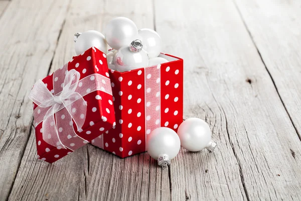 Red Christmas gift box full of xmas white bauble, on wood backgr — Stock Photo, Image