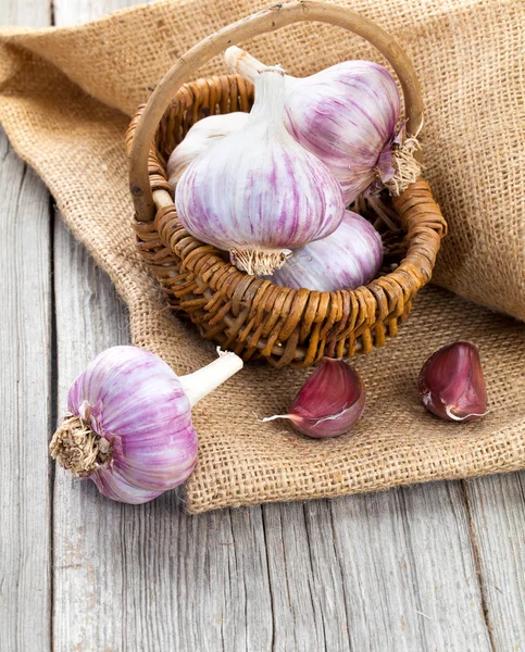 Garlic on Burlap sack, on wooden background — Stock Photo, Image