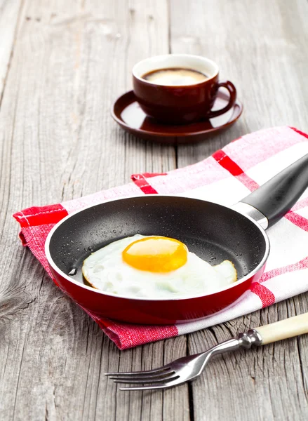 Fried egg in a frying pan, on an old wooden table — Stock Photo, Image