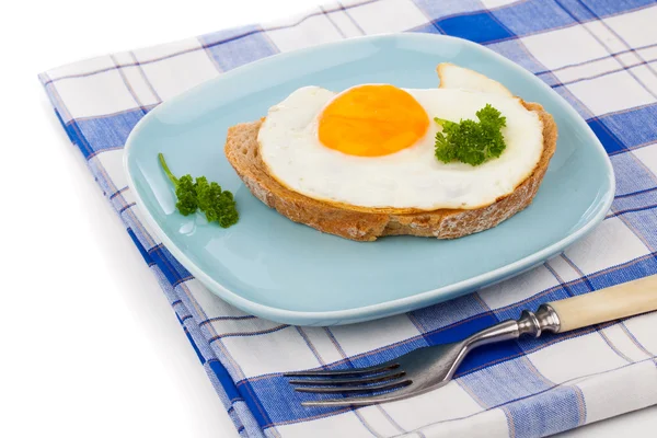 Жареное яйцо в голубой тарелке с вилкой, на белом фоне — стоковое фото