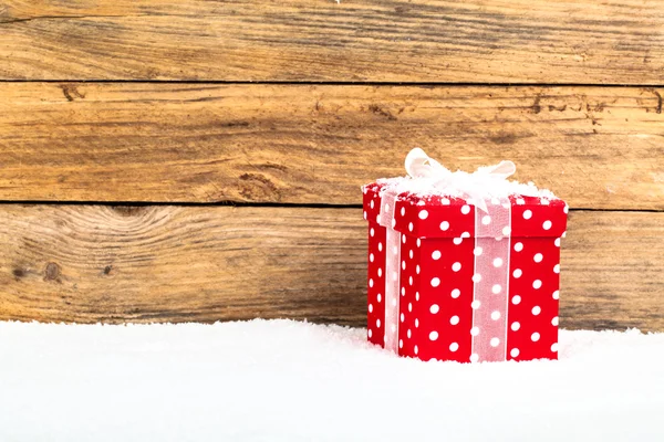 Red gift for christmas on a wooden background with snow — Stock Photo, Image