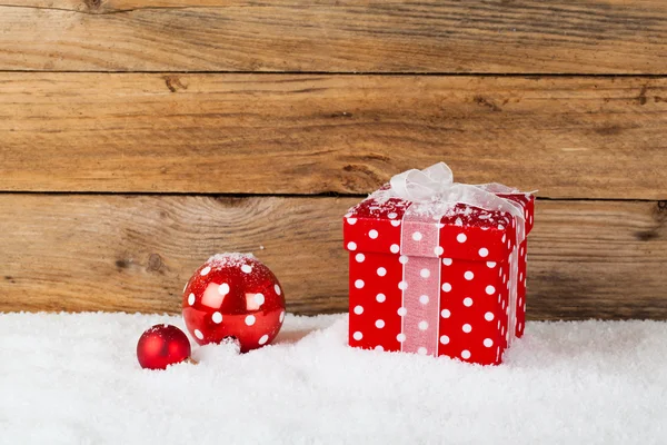 Рождество красный подарок со снегом, на деревянном фоне — стоковое фото