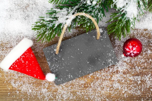 Tabla negra de pizarra sobre fondo rústico de madera con nieve — Foto de Stock