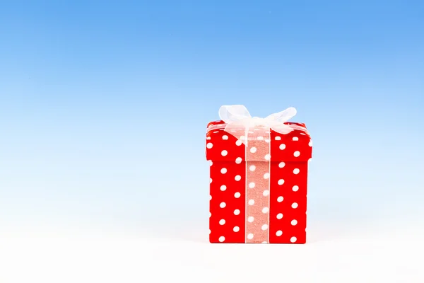 Red gift box, polka dots with bow on blue background — Stock Photo, Image