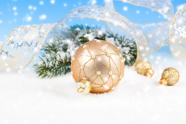 Kerstballen met lint op sneeuw, op blauwe achtergrond — Stockfoto