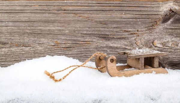 Vieux traîneau rustique en bois, sur la neige, fond en bois — Photo