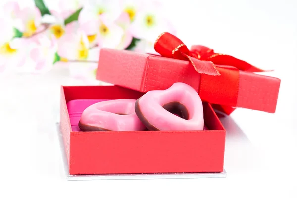 Galletas de corazón rosa para el día de San Valentín en regalo rojo, en la espalda blanca — Foto de Stock