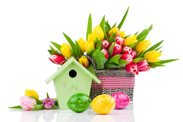 Huevos de Pascua con flores de tulipanes y pajarera, en un fondo blanco —  Fotos de Stock