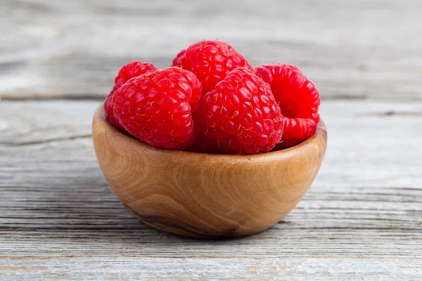 Raspberries in wooden bowl, on wooden background — Stock Photo, Image