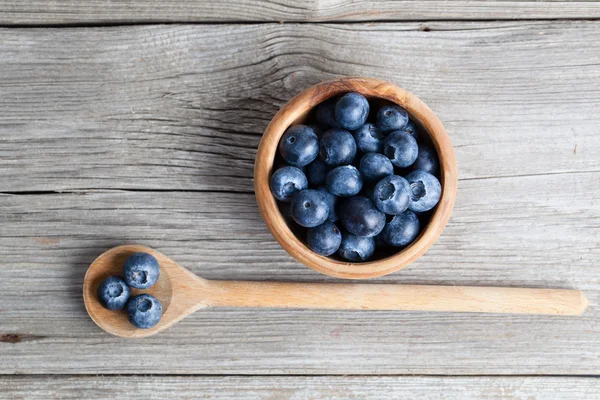 Blueberries on a wooden bowl, spoon. on wooden background — Stock Photo, Image