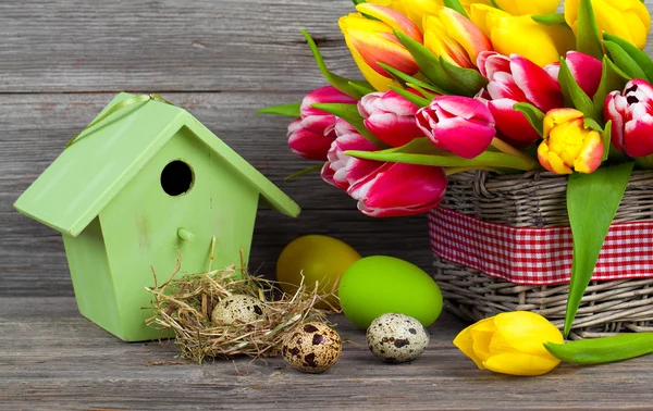 Wielkanoc dekoracje z jajka, birdhouse i tulipany. drewniane tła — Zdjęcie stockowe