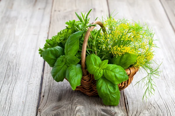 Groene kruiden in rieten mand, op houten achtergrond — Stockfoto