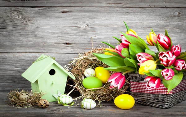 Decoración de Pascua con huevos, pajareras y tulipanes. backgr de madera —  Fotos de Stock