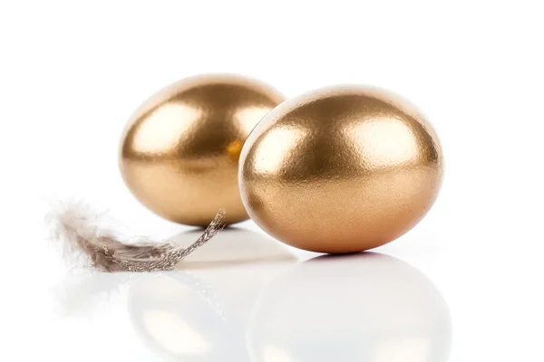 Ovos dourados e penas isoladas sobre fundo branco — Fotografia de Stock