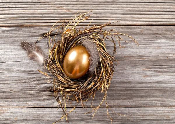 Złote jaja w gnieździe na ciemne tło drewniane — Zdjęcie stockowe