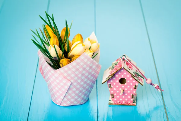 Żółte krokusy i birdhouse na niebieskim tle drewniane — Zdjęcie stockowe