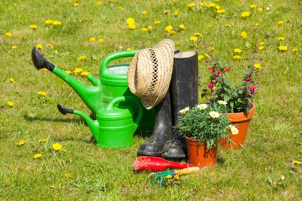 Gardening tools and a straw hat on the grass in the garden — Stock Photo, Image