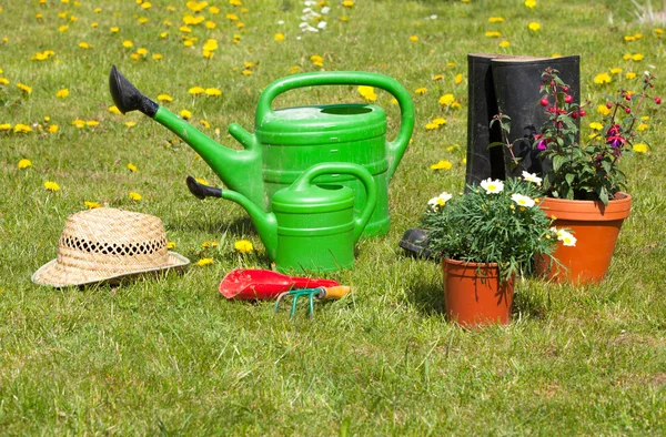 Gardening tools and a straw hat on the grass in the garden — Stock Photo, Image