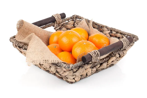 Een rieten mand vol frisse oranje vruchten, geïsoleerd op een witte — Stockfoto