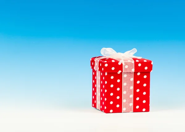 Red gift box, polka dots with bow on blue background — Stock Photo, Image