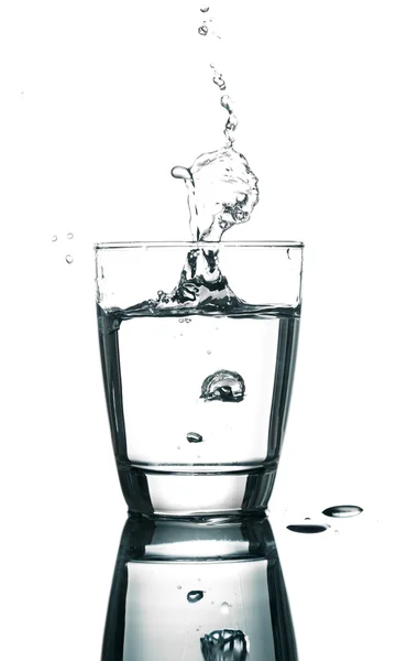 Nalévání vody na sklenici na bílém pozadí — Stock fotografie