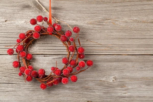 Рождественский венок из красных ягод на деревянном фоне — стоковое фото