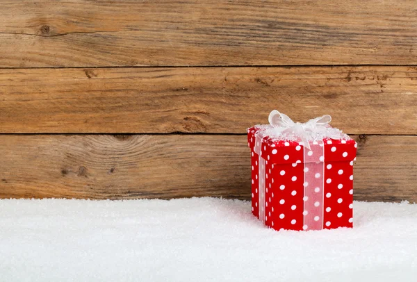 Christmas red gift with snow, on wooden background — Stock Photo, Image