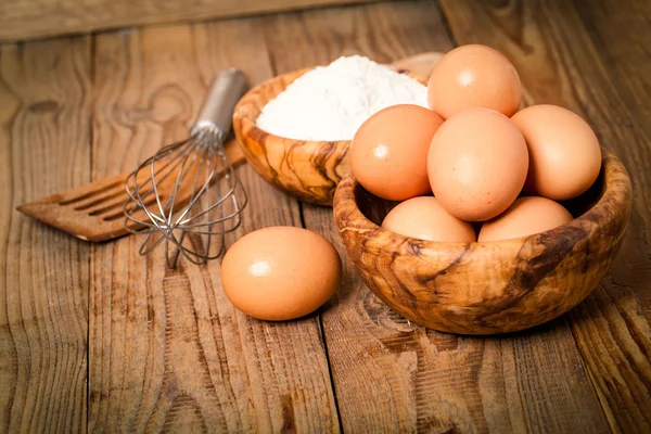 Meel en eieren, ingrediënten voor het bakken. op houten achtergrond — Stockfoto