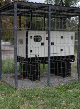 Installation of a large industrial fuel-fired generator on a green lawn. A mobile power source, backup equipment for power plants. 