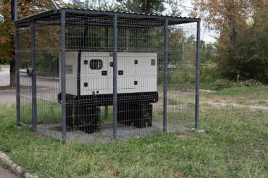 Installation of a large industrial fuel-fired generator on a green lawn. A mobile power source, backup equipment for power plants.