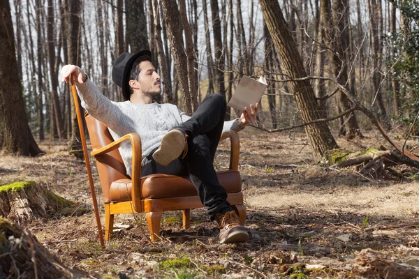 Homem lendo um romance na floresta — Fotografia de Stock