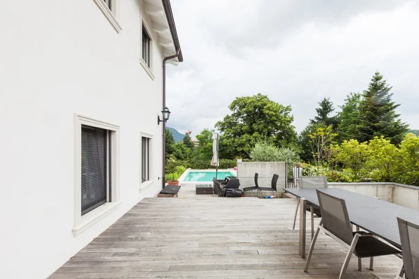 Land blaues Haus mit Betonboden Patio-Bereich mit Stühlen. — Stockfoto