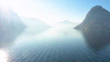 Arka planda Melide köprüsü olan Lugano Gölü 'nün havadan görüntüsü. İsviçre 'de İHA' yla havadan atış yapan Dolly. Dalgaların suyunu kapat.