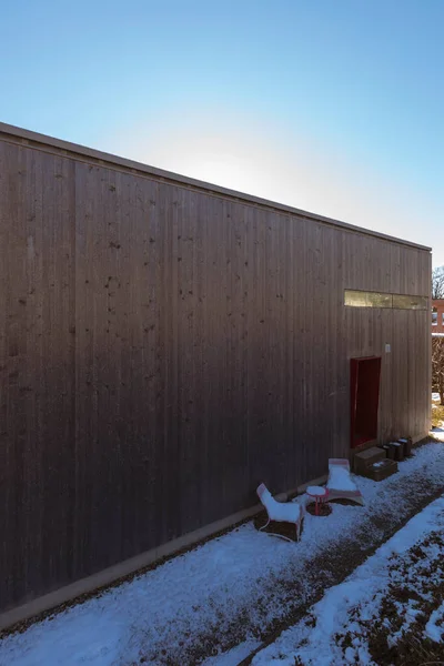 現代の小さな木造住宅の冬の外観 入口には雪のある二つの庭の椅子 — ストック写真