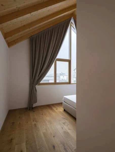 Bedroom interior detail of a mountain house. It's snowing outside and the ceiling and floor are smooth