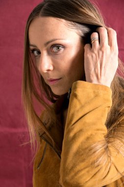 Saçlarına dokunurken makyajsız, şehvetli bir genç kadının yakın çekimi.