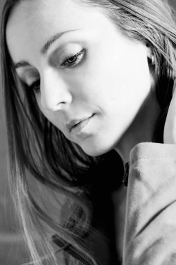 Makyajsız, şehvetli bir genç kadının saçına dokunurken aşağıya baktığı yakın plan. Kel ve beyaz portre