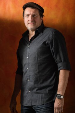 Düğmeleri iliklenmemiş gömlekli 50 yaşında bir adamın portresi. Ciddi tavır.