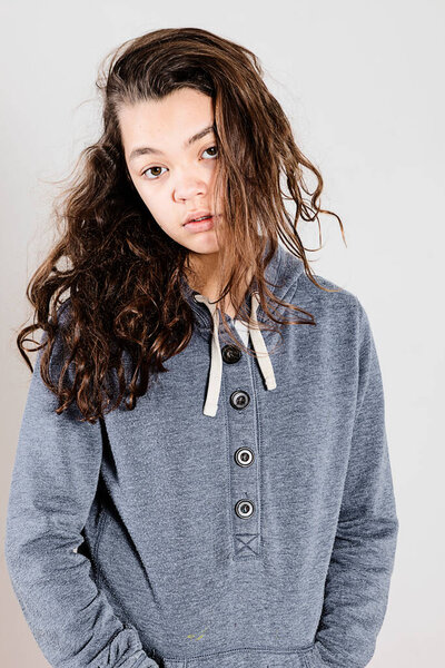 Teen with lazy face wearing a blue sweatshirt while posing