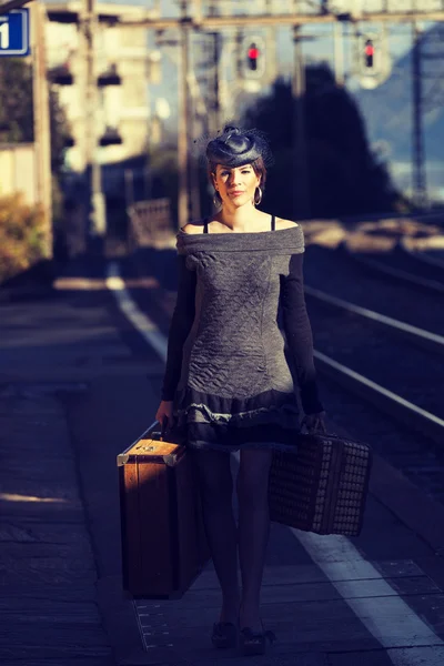 Mujer con equipaje vintage en la estación de tren — Foto de Stock