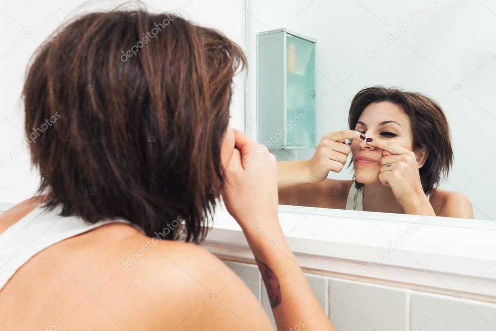 Woman you squeeze a pimple in the mirror