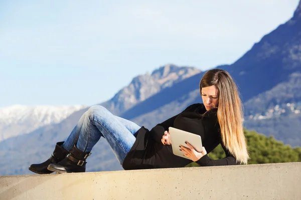 Woman with tablet lying in outdoor — Stock Photo, Image