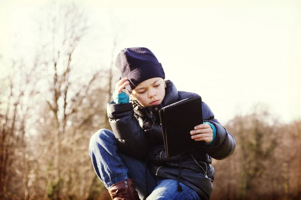 Kind sucht sein Tablet im Freien — Stockfoto