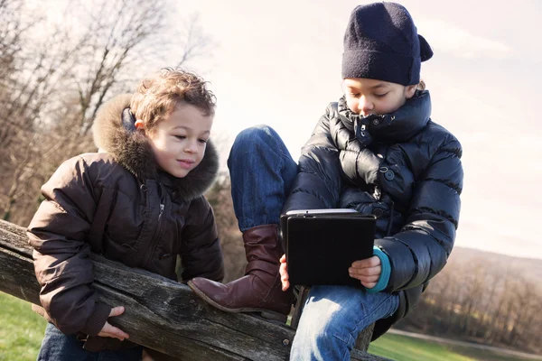 Duas crianças brincando com o tablet ao ar livre — Fotografia de Stock