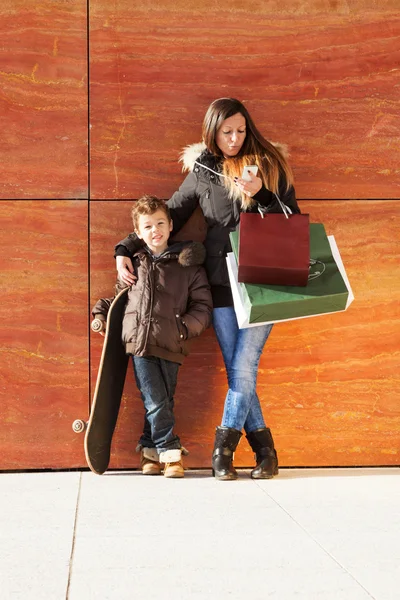 Chica con niño esperando con bolsas de la tienda — Foto de Stock