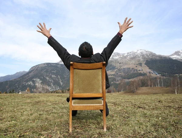 Man sits on a chair into the wild — Stock Photo, Image