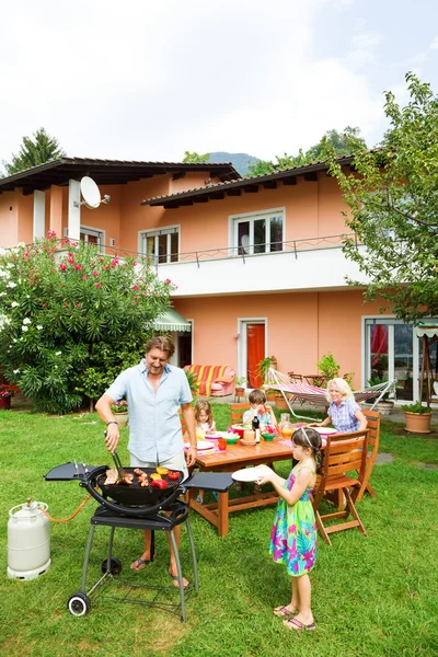 Família fazendo um churrasco no jardim, comendo — Fotografia de Stock